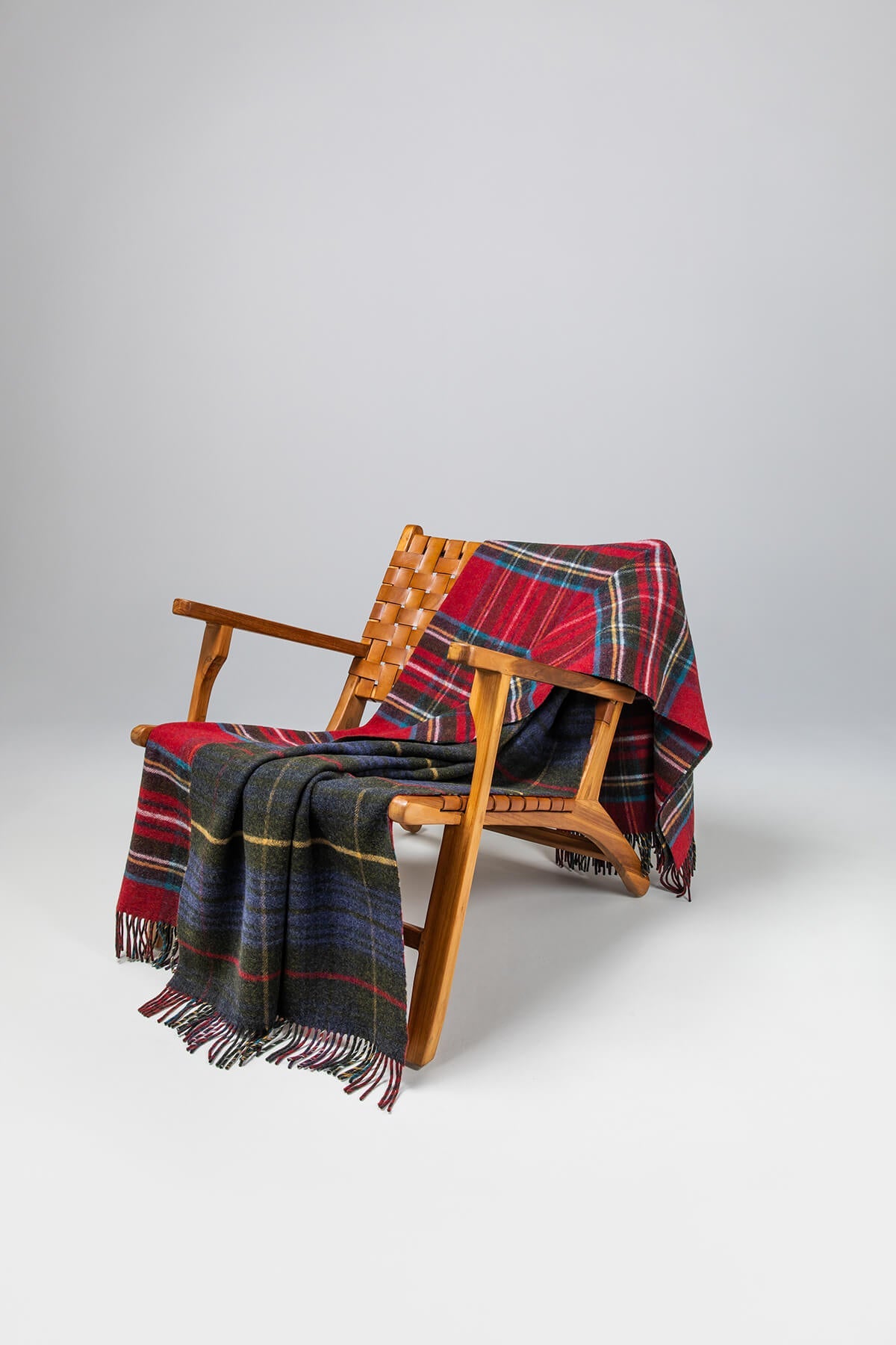 Johnstons of Elgin’s Double Face Hunting Stewart Check Lambswool Throw on brown chair on a grey background WD000021XU0033N/A