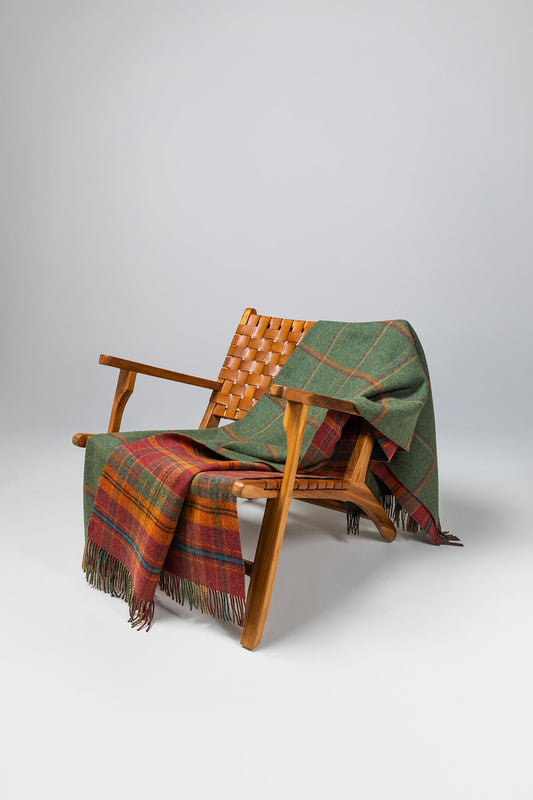 Johnstons of Elgin’s Double Face Dunoon Check Lambswool Throw on brown chair on a grey background WD000021XU0036N/A