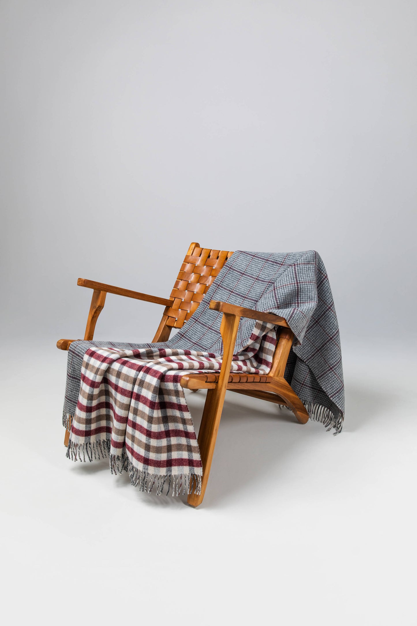 Johnstons of Elgin’s Double Face Tay Check Lambswool Throw on brown chair on a grey background WD000021XU0286N/A