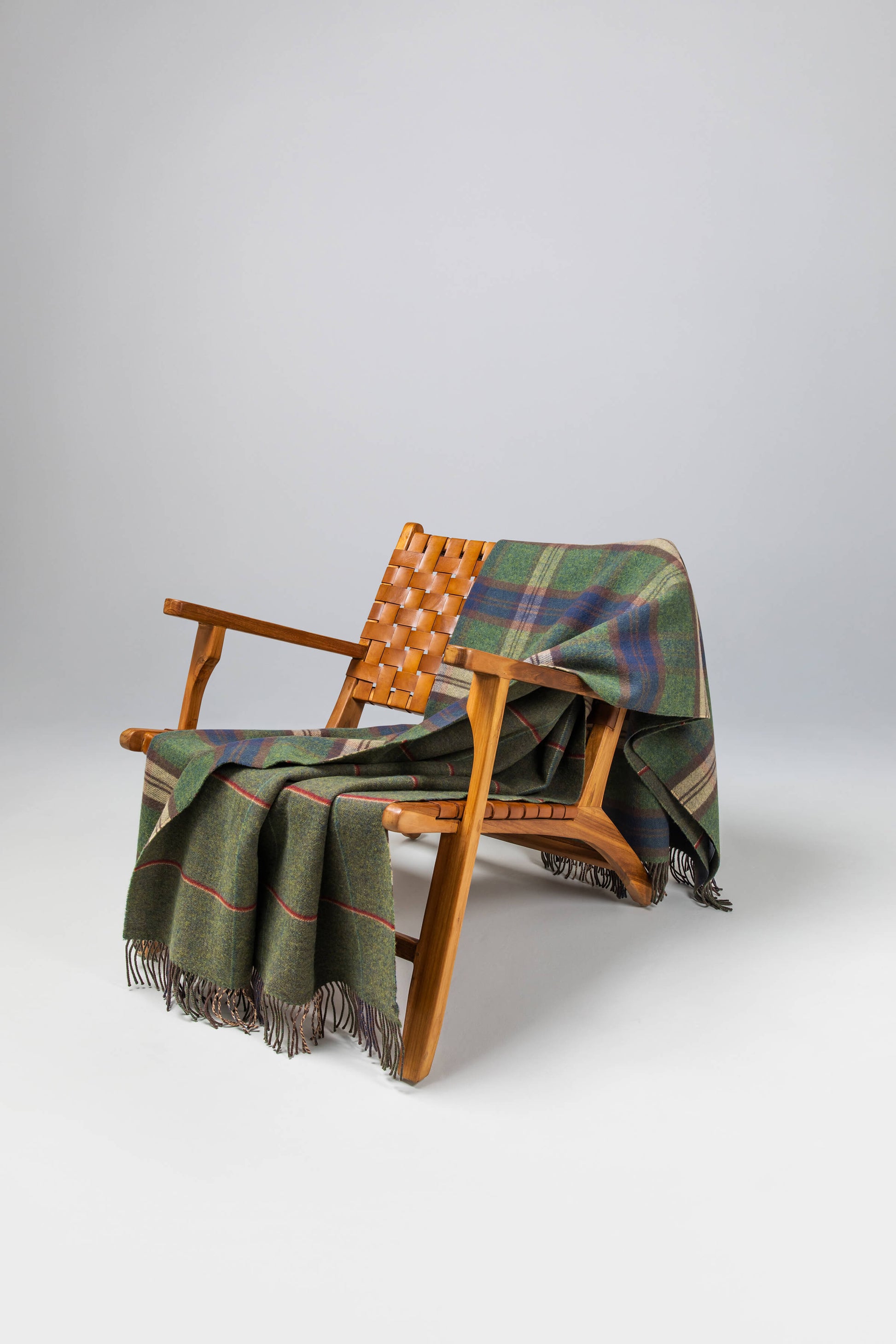 Johnstons of Elgin’s Scottish Heritage Double Face Forth Check Lambswool Throw on brown chair on a grey background WD000021XU0287N/A