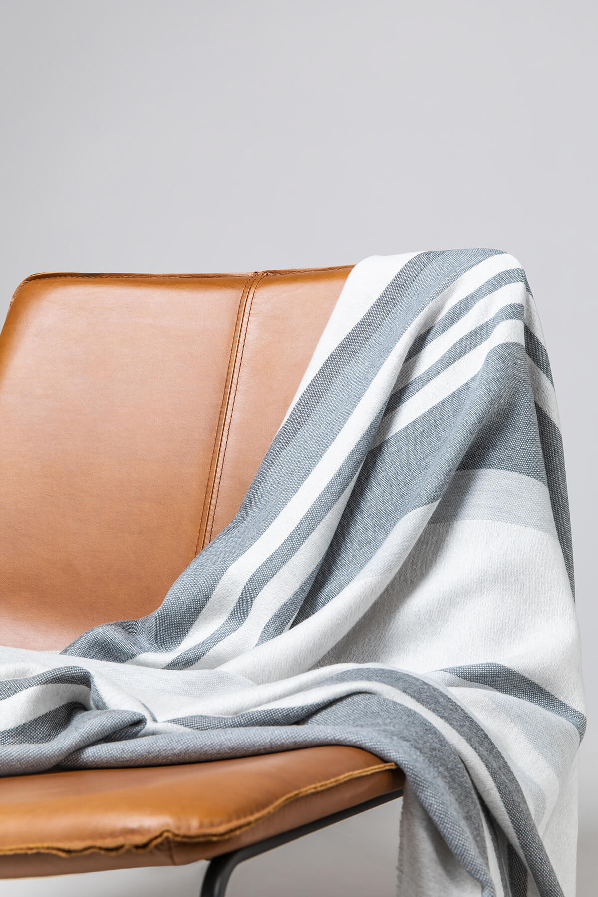 Johnstons of Elgin’s Bold Stripe Grey Merino Throw on brown chair on a grey background WD000257RU6994ONE