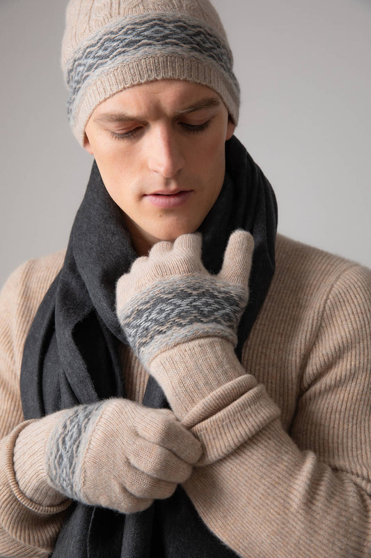 Johnstons of Elgin’s Fairisle Hat and Gloves Giftset in Oatmeal on a model wearing a natural cashmere jumper and grey cashmere scarf on a grey background AW23GIFTSET2B